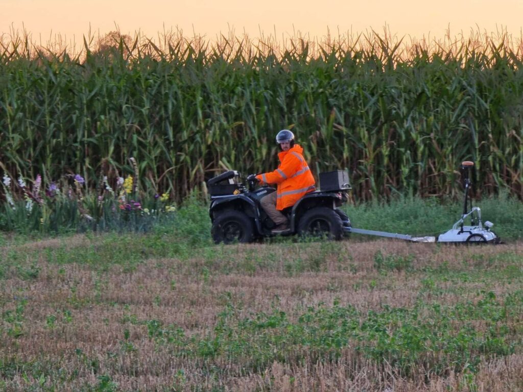 Badania georadarem doczepionym do quada, w tle pole kukurydzy.