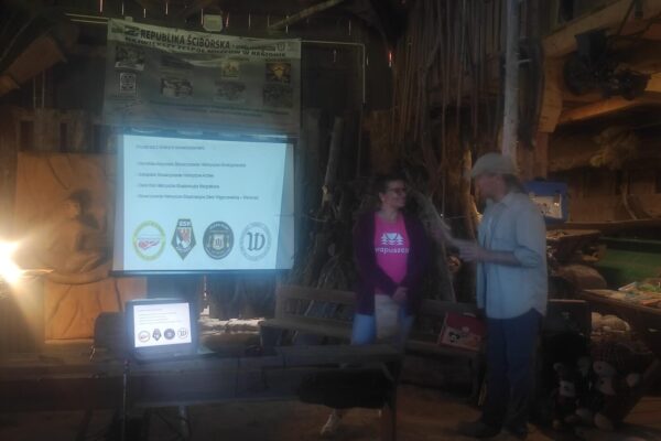 3_Easy-Resize.com Iwona wygłasza referat, widać na prezentacji logotypy grup poszukiwaczy z nami współpracyjących