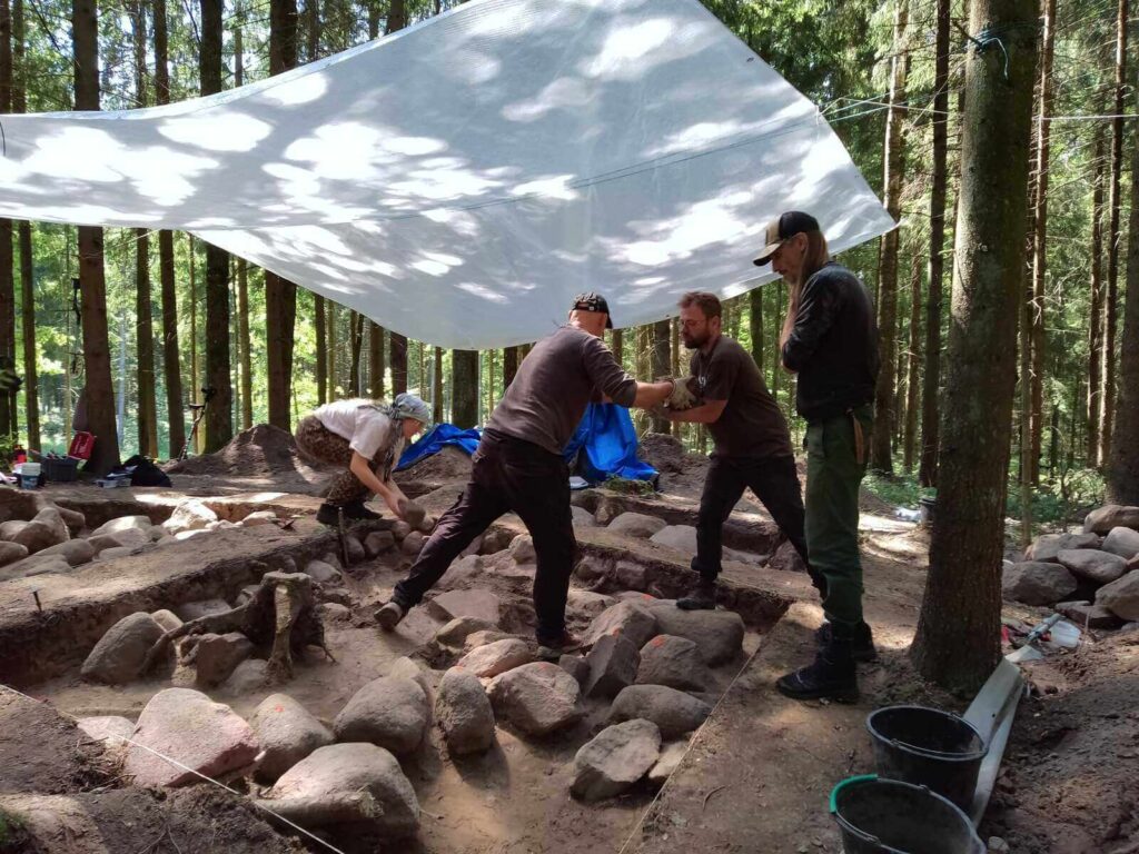 cztery osoby pracują przy wyjmowaniu kamieni z bruku po ich zniwelowaniu i zeskanowaniu