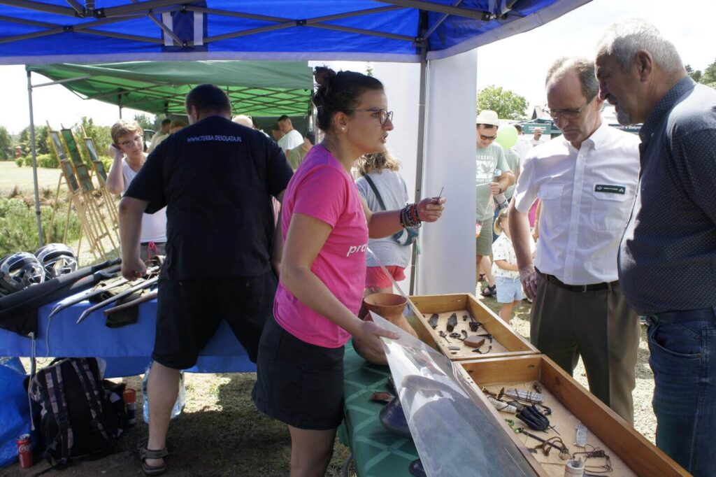 Edukatorka opowiada o zabytkach i replikach leśnikom.