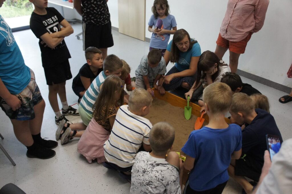 dzieciaki szukają replik w piaskownicy archeologicznej