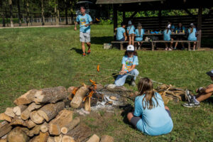 dzieci pieką kiełbaski na ognisku