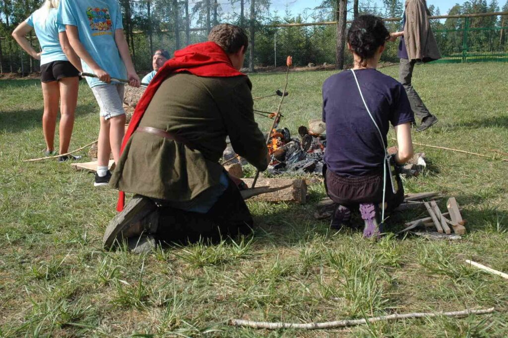 Piotrek i Ada widziani od tyłu smażą kiełbaski i chebek