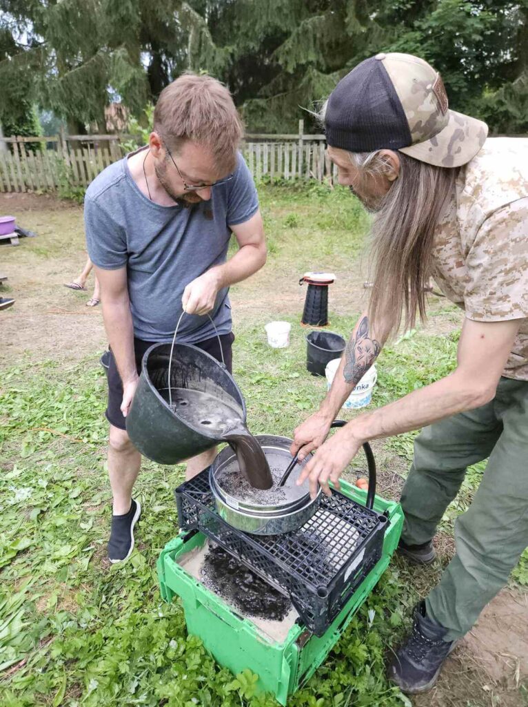 Malik trzyma sito a Bartek przelewa glebę z wodą