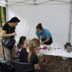 Iwona pokazuje dzieciom, jak robić paciorki z modeliny.