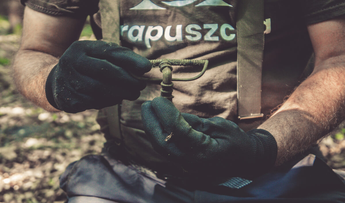 Zbliżenie na dłonie znalazcy, w których trzyma zapinkę kuszowatą