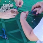 Zbliżenie na ręce osób tworzących biżuterię z miedzianego drutu