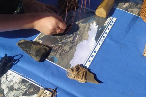 f Zbliżenie na stół z rekonstukcjami zabytków i krzemieniami oraz zdjęciami