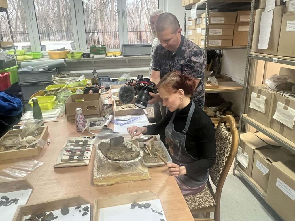 Monika eksploruje urnę, a Bartek nagrywa jej prace do filmu dokumentalnego.