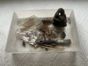 Sklejony ciężarek w pudełku, wokół resztki, piasek i narzędzia