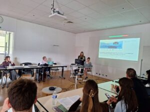 Agata i Iwona przedstawiają referat, na pierwszym planie siedzący słuchacze