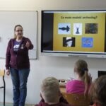 Edukatorka wskazuje na chętnego do odpowiedzi podczas wykładu.