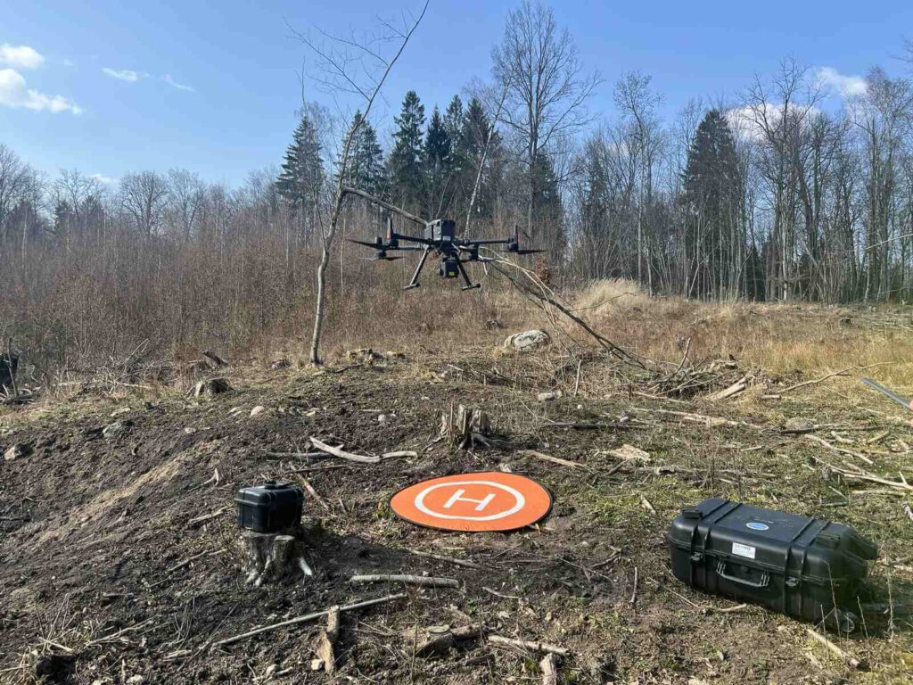Dron ląduje na wyrębie na specjalnym pomarańczowej macie.