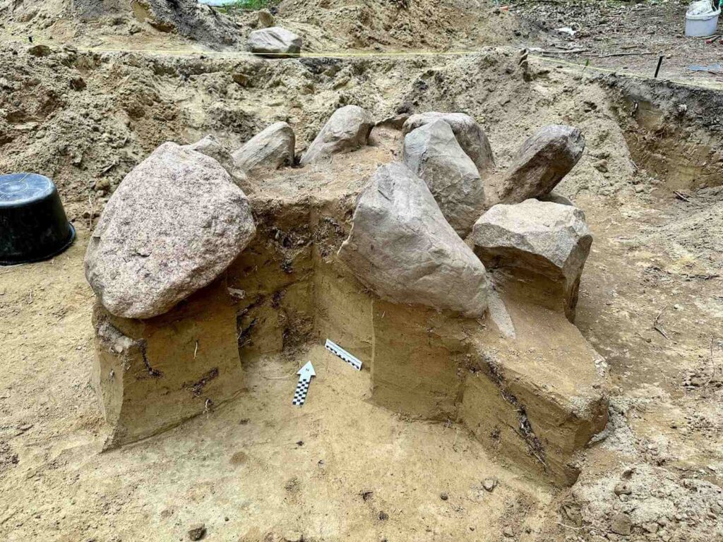 Widok na odczyszczone kamienie grobu centralnego w kurhanie. W środku pusto, brak urn.