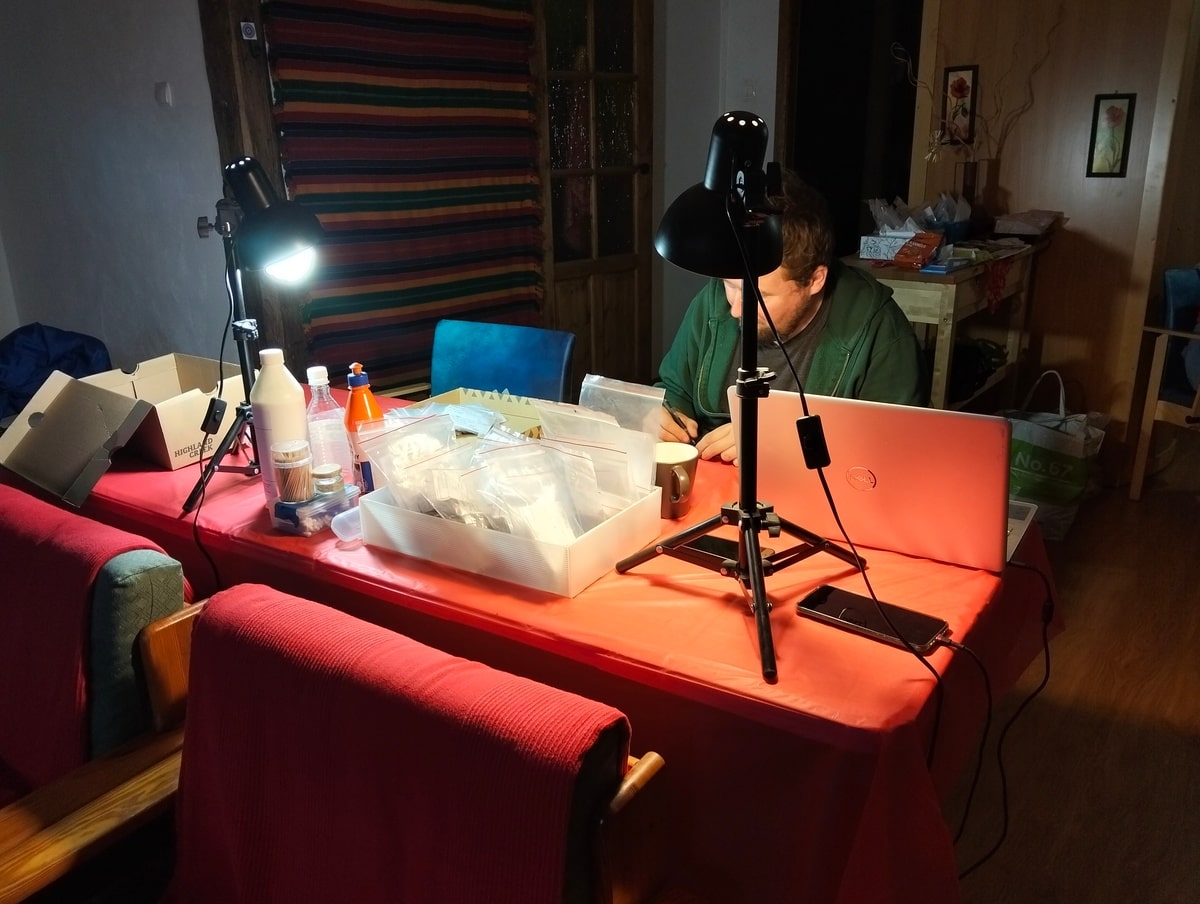 Paweł opracowuje ceramikę. Wokół na stole niezbędny sprzęt, mocne lampy, klej itd.