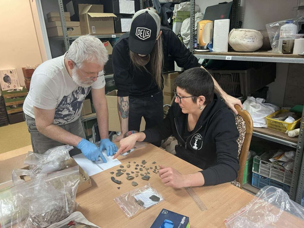 Paweł, Przemek i Agata rozmawiają nad fragmentami naczynia do sklejenia.