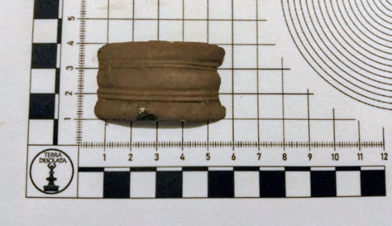 Fragment bransolety zdobionej liniami leży na podkładce z miarką