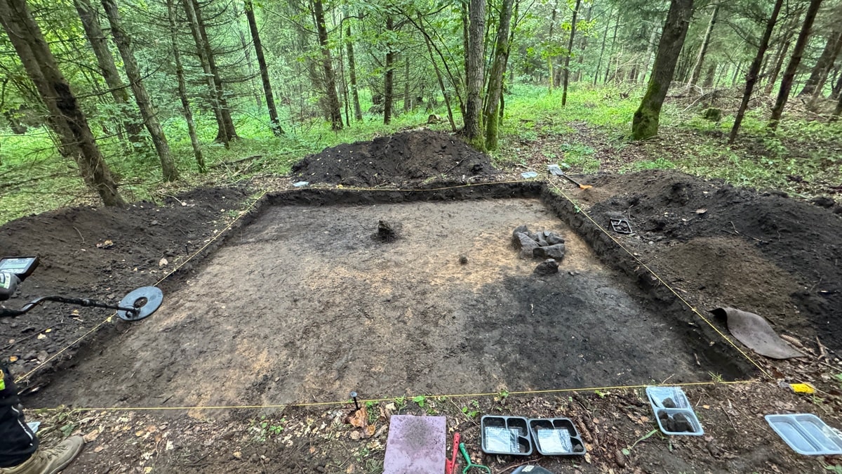 Widok na otwarty wykop z widocznymi ciemnymi plamami obiektów