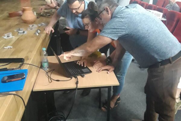 Goście i prowadzący stojąc pod sceną sprawdzają dane w laptopie