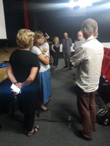 Uczestnicy wykładu wymieniają się opiniami stojąc pod sceną