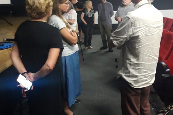 Uczestnicy wykładu wymieniają się opiniami stojąc pod sceną