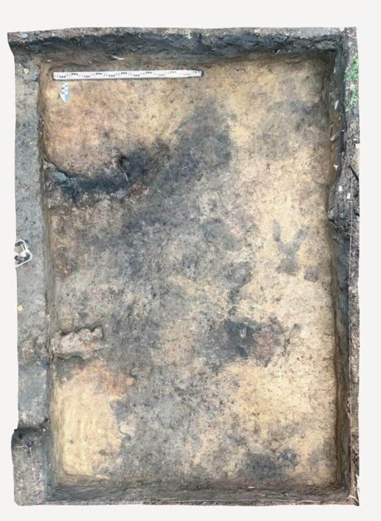 Widok na plan prostokątnego pieca, widać ciemne wypełnisko i pasy polepy.