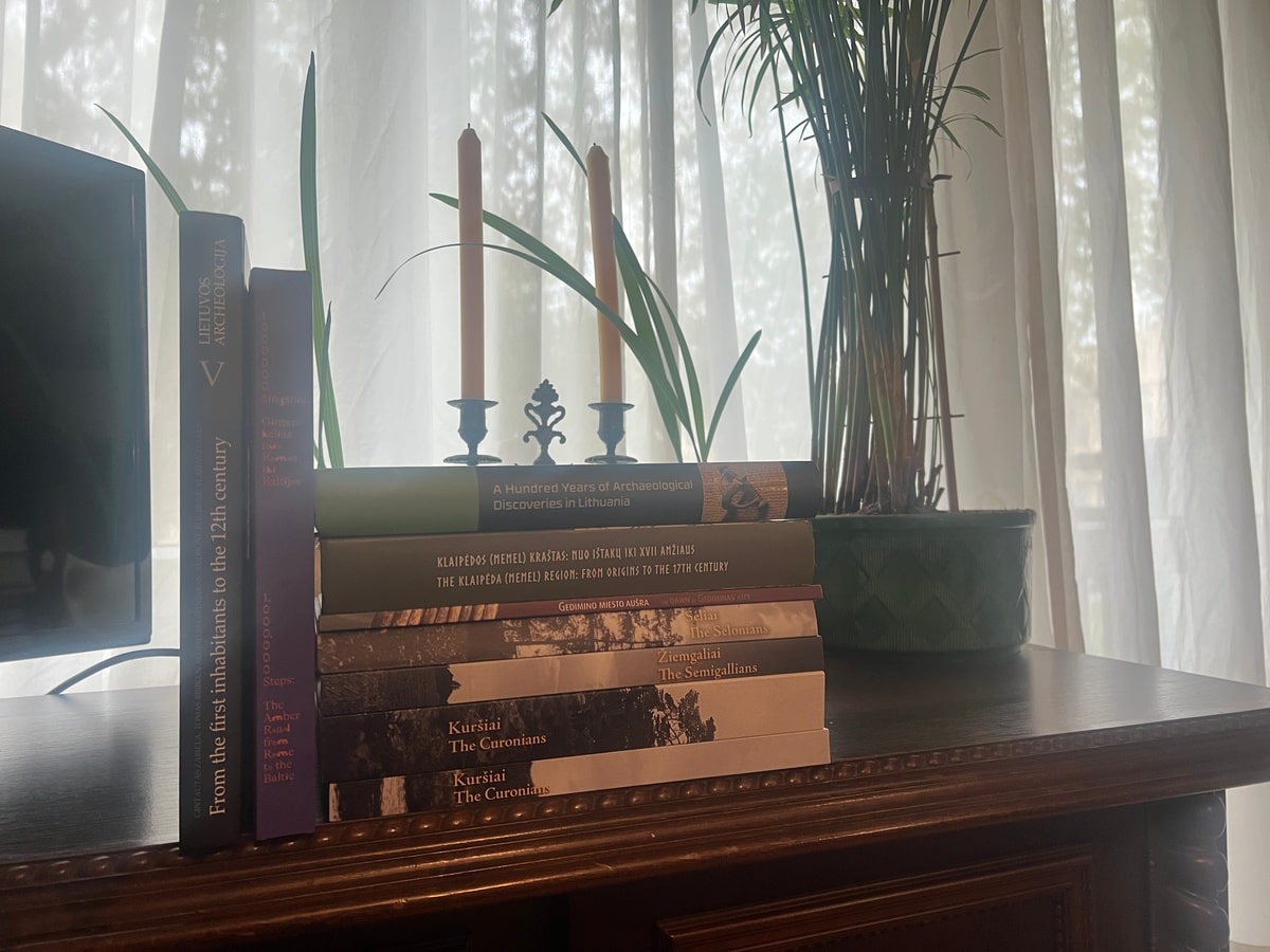 Kupka książek ukazana na tle okna i świec