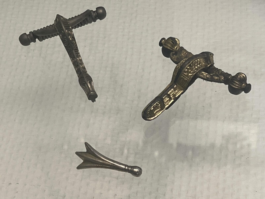 Trzy brązowe zapinki na wystawie muzealnej.