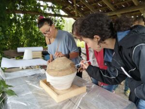 Iwona, Ania i Ada odczyszczaja pędzelkami urnę z piasku