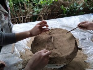 Zbliżenie na urnę i dłonie osób eksplorujących ją patyczkami