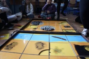 Zbliżenie na odsłoniętą planszę gry. Widać rzekę, kurhany, zarysy obiektów archeologicnzych.