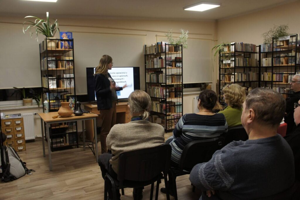 Zdjęcie z tyłu sali na prelegentkę i słuchaczy.