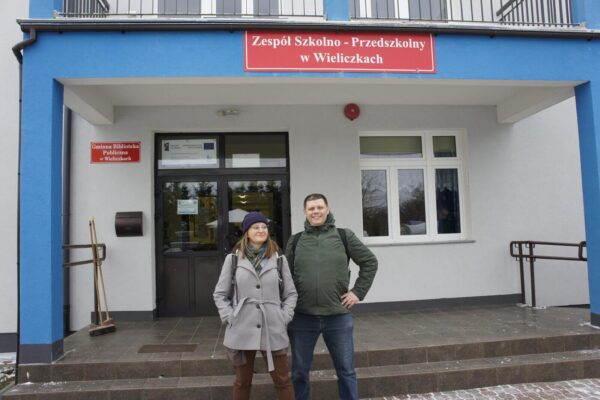 Monika i Piotrek pozują na tle szkoły w Wieliczkach.