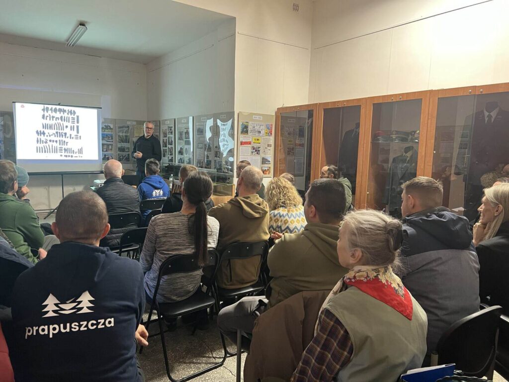 Widok na salę i siedzących gości słuchających wykładu.