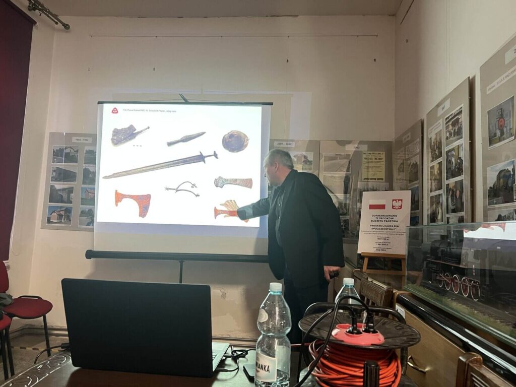 Prelegent omawia slajd z przykładami znalezisk archeologicznych