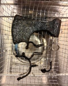 Jeden z mniejszych toporów i inne zabytki żelazne leżą na sicie w pracowni konserwatorskiej.