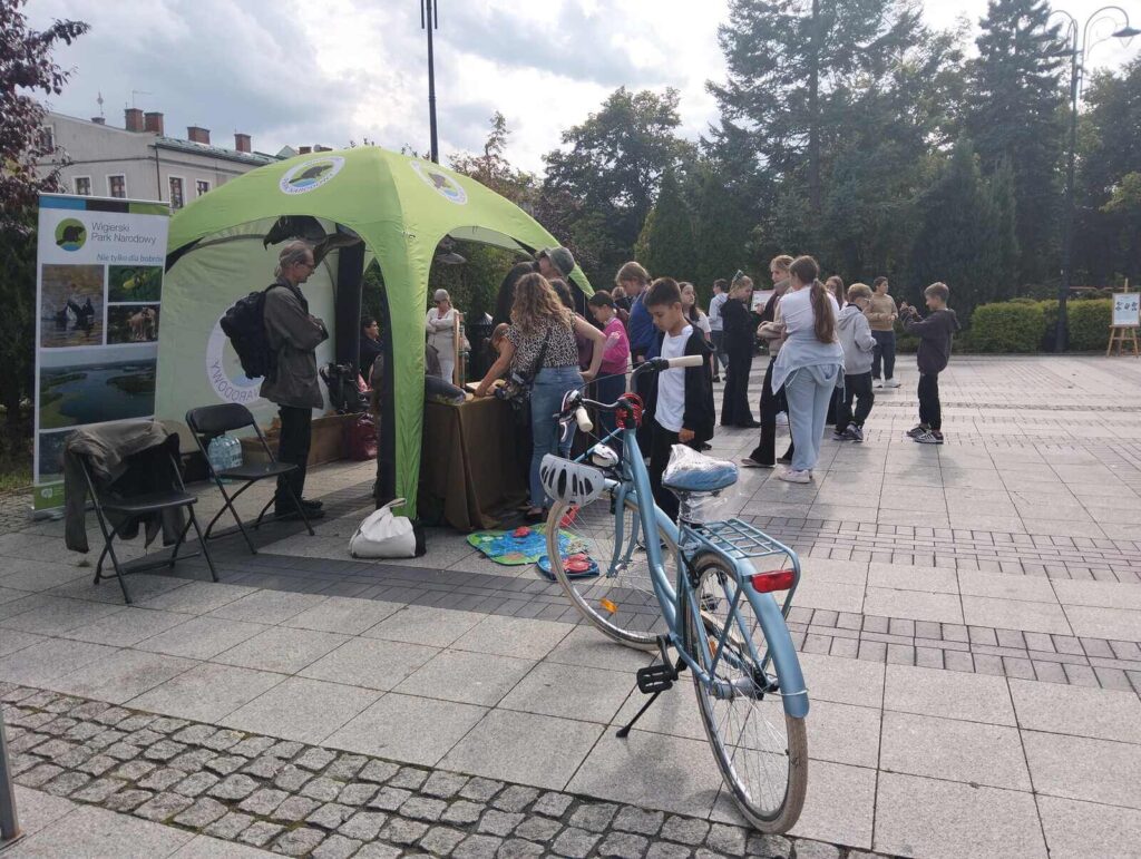 Na stoisku Wigierskiego Parku Narodowego trwają warsztaty, na pierwszym planie zaparkowany dziecięcy rower