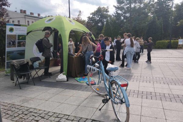 sss_Easy-Resize.com Na stoisku Wigierskiego Parku Narodowego trwają warsztaty, na pierwszym planie zaparkowany dziecięcy rower